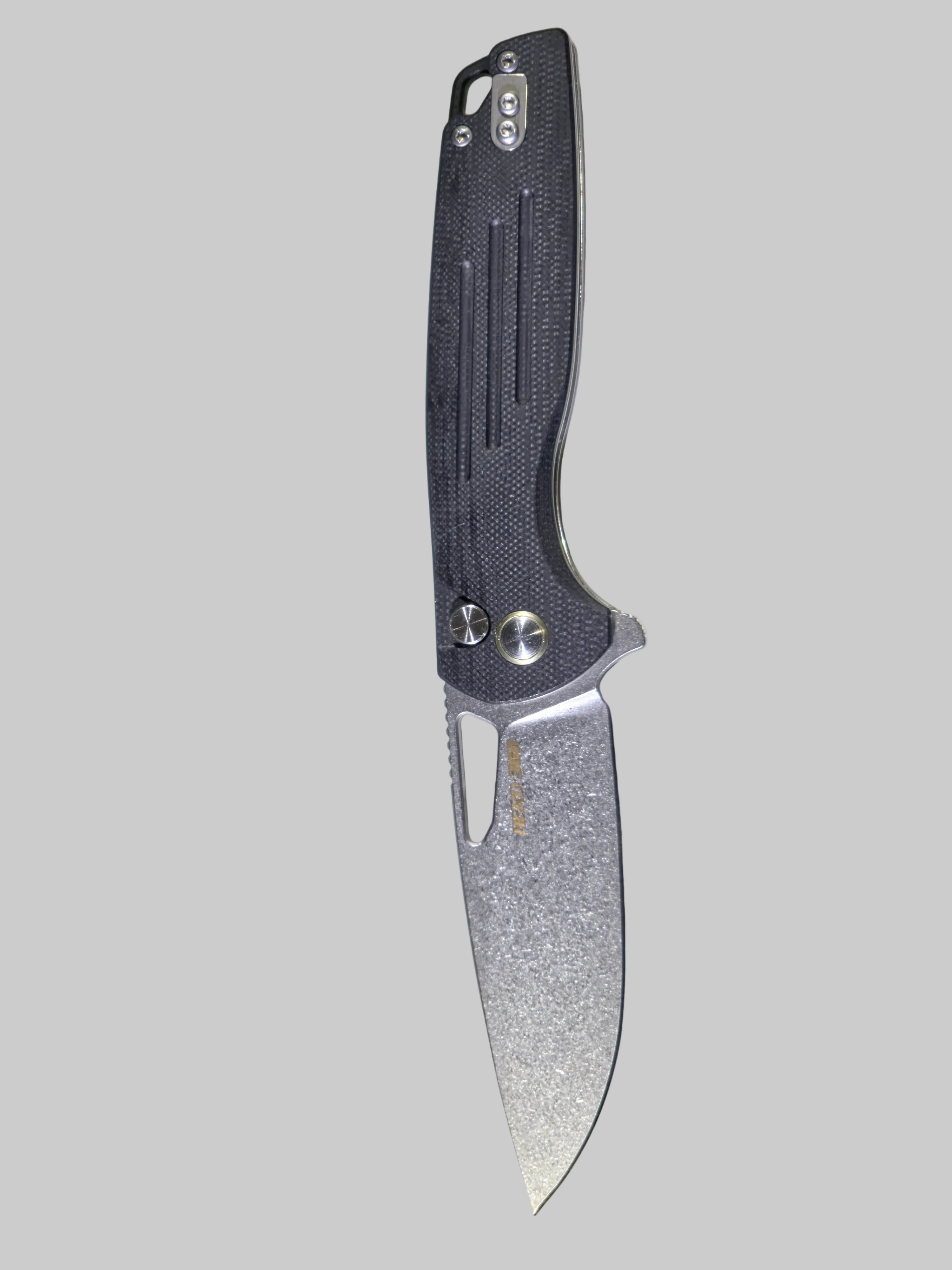 Folding knife with a textured blade on a white surface