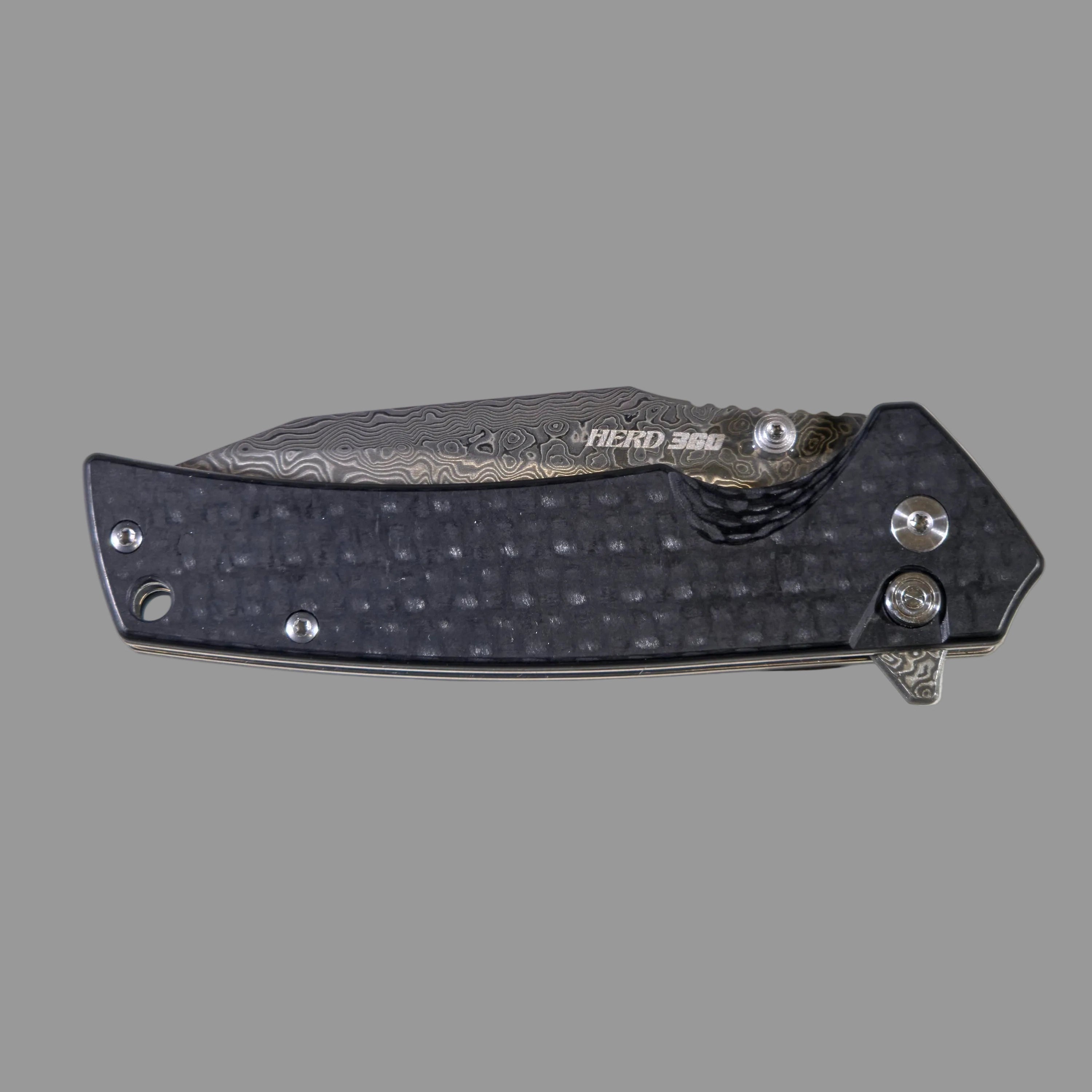 Folding knife with carbon fiber pattern on a light gray surface