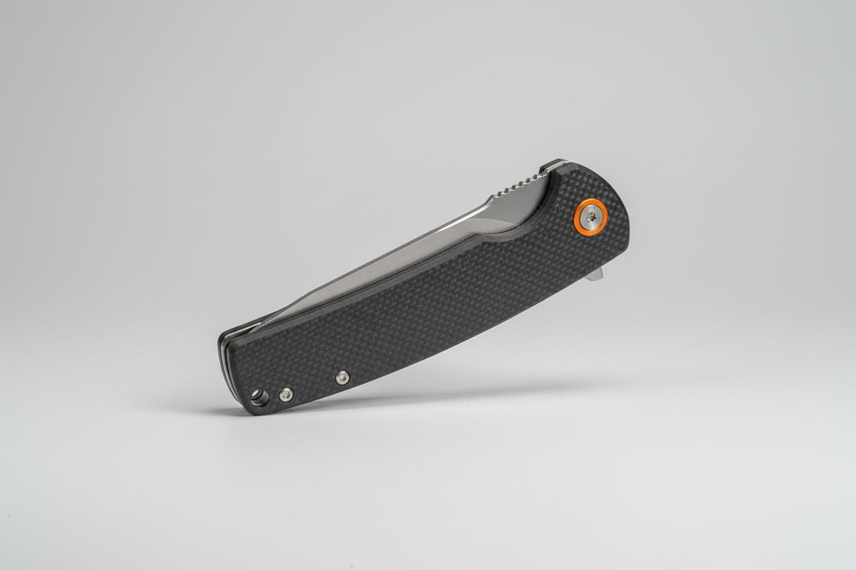Folding knife with a textured handle on a white surface with a blurred background